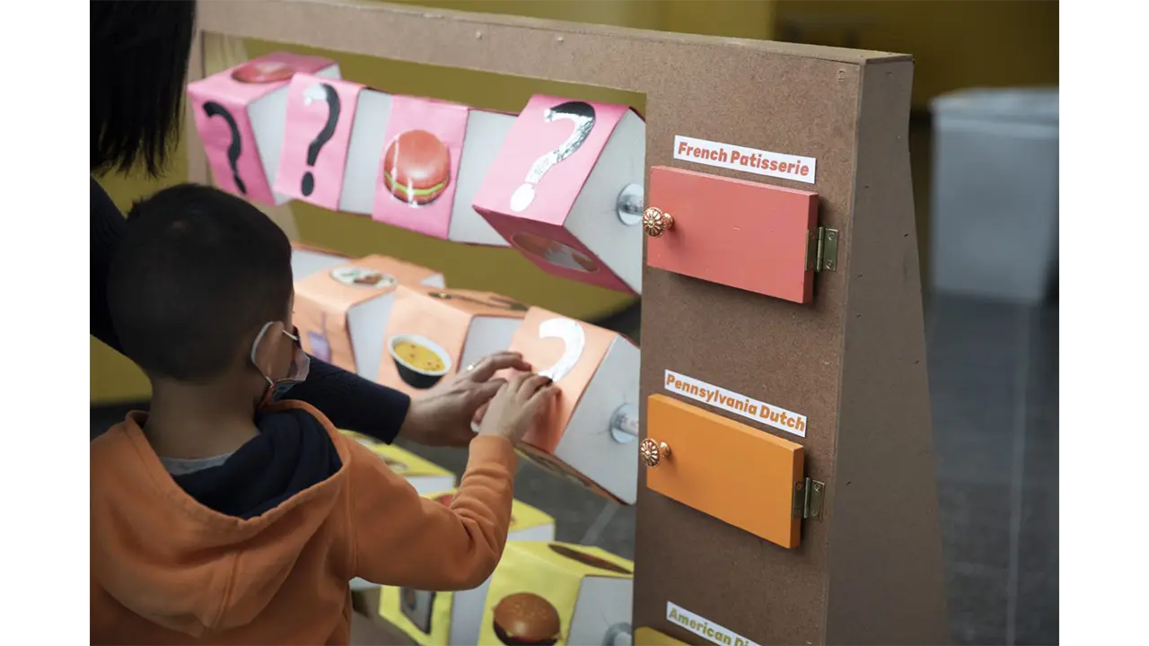 Child playing with spinning block game created to represent the food and cultures at Reading Terminal Market.